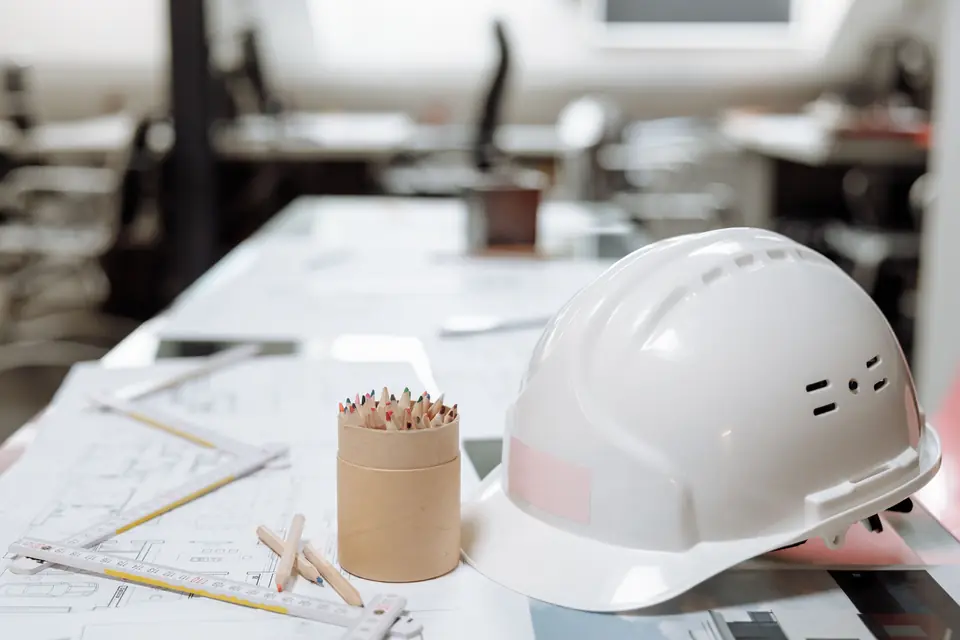 Drawings, pencils and a site helmet on a desk